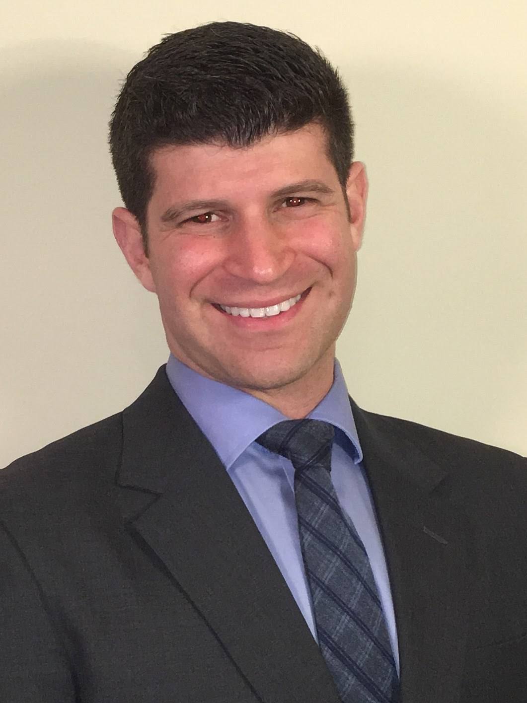 Professional portrait of Dr. Elan Goldwaser in a suit