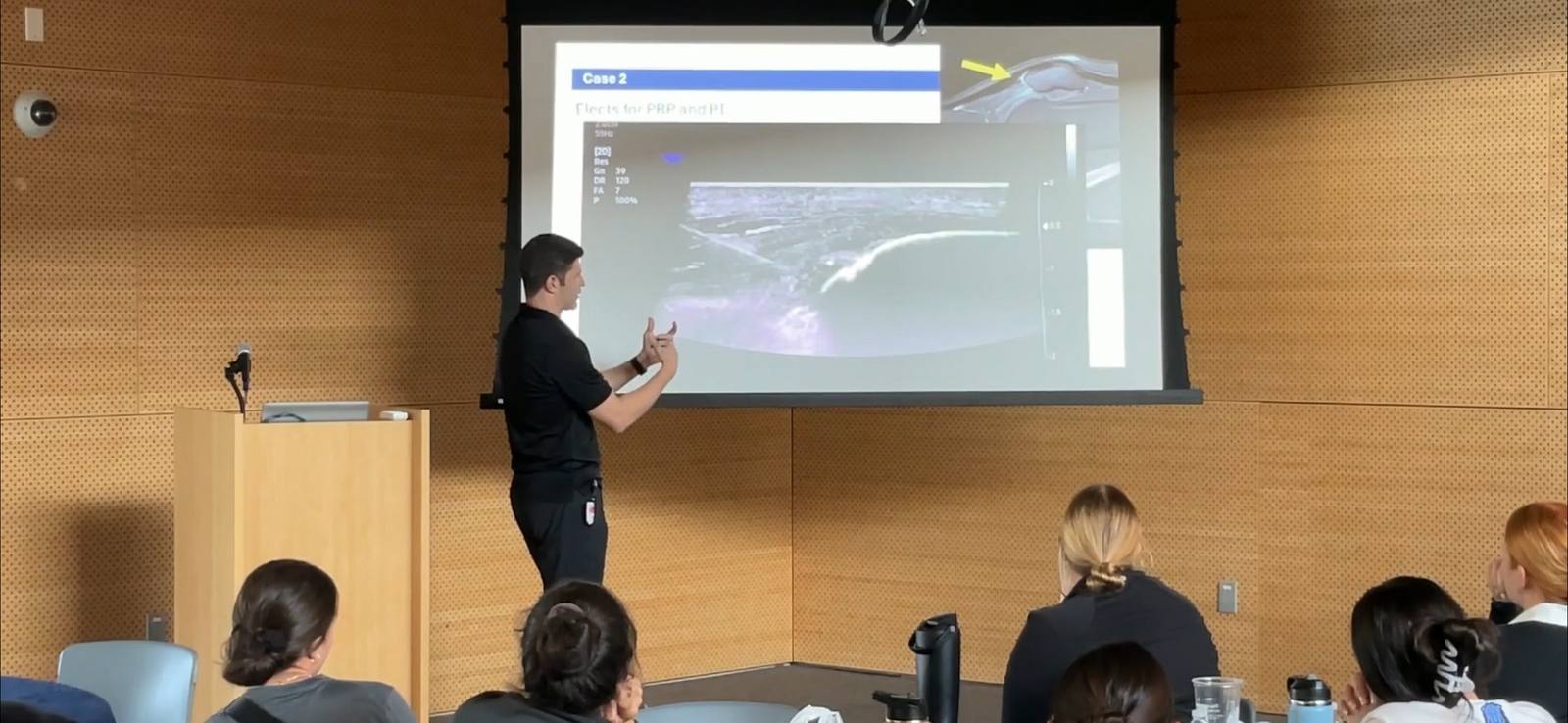 Dr. Goldwaser presenting ultrasound case images to a lecture-hall audience
