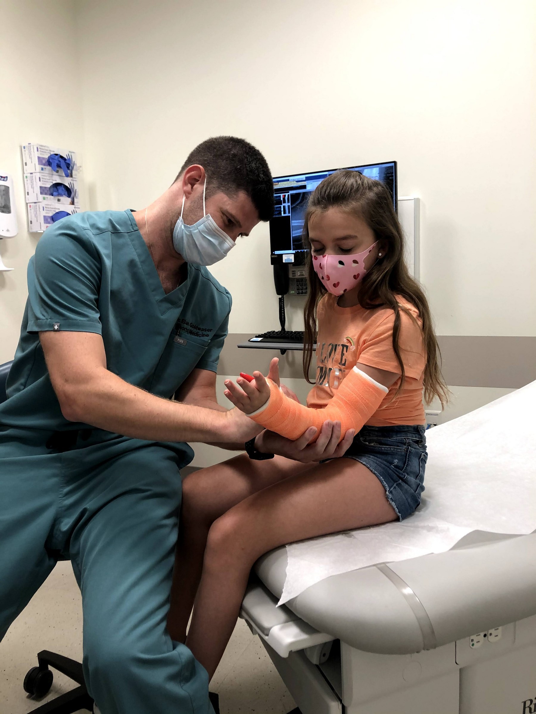 Dr. Goldwaser signing a young patient’s orange cast