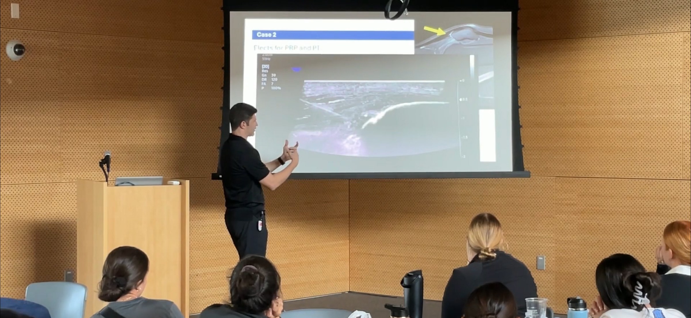 Dr. Goldwaser presenting ultrasound case images to a lecture-hall audience